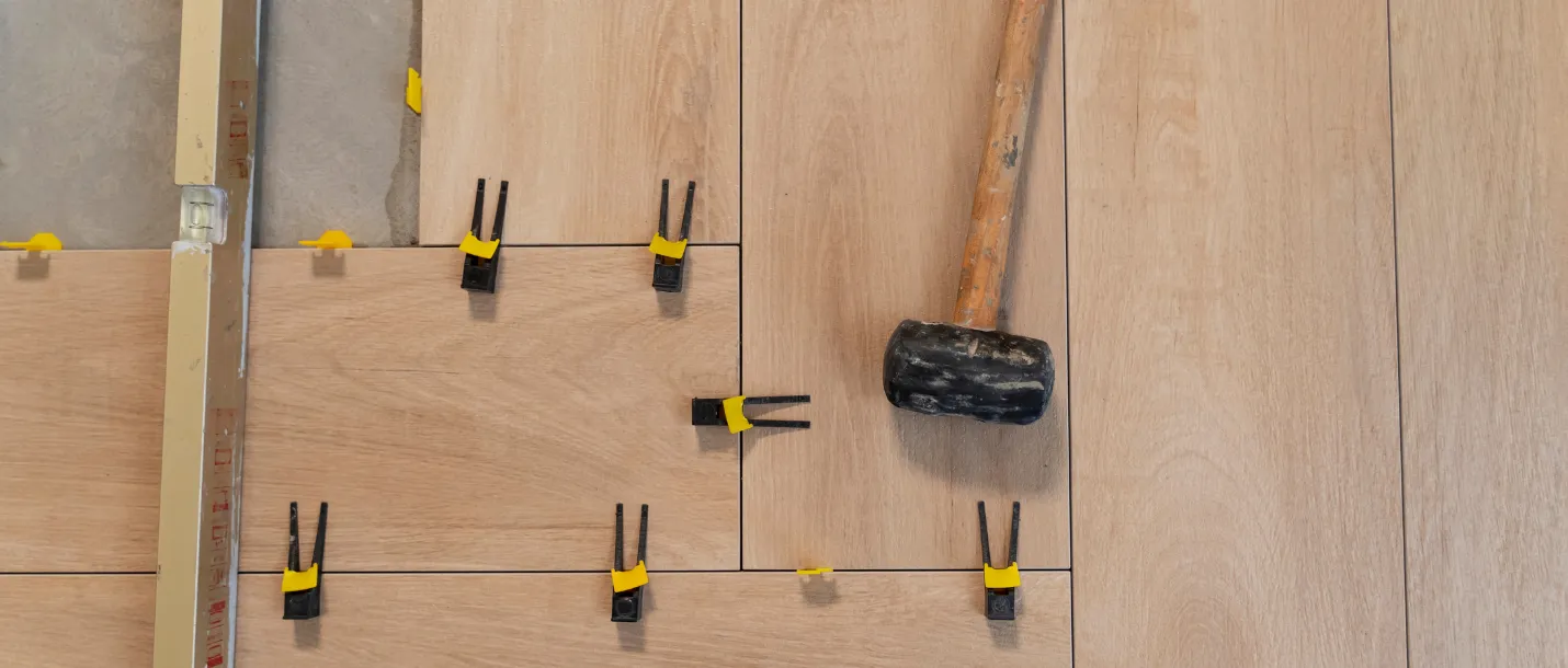 Worker aligning wood flooring planks during residential floor installation project